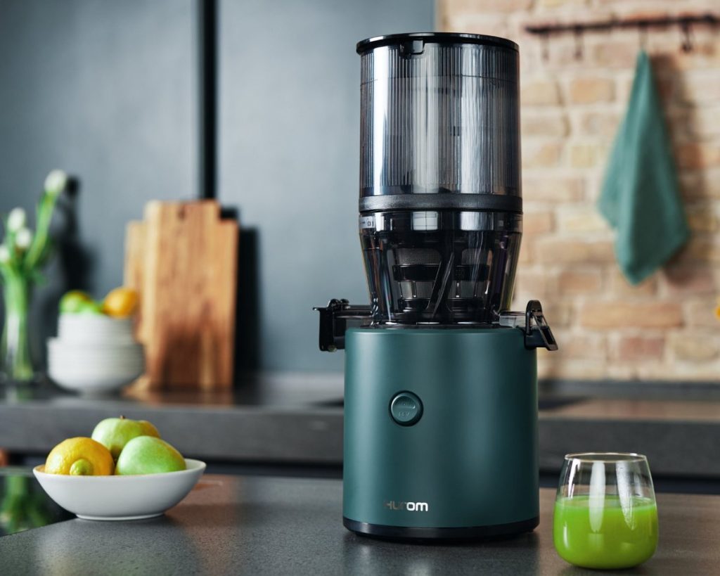 Hurom H320N cold press juicer with a fresh green juice with apples and lemons on the counter — example of nutrient-rich juice used during a juice fast