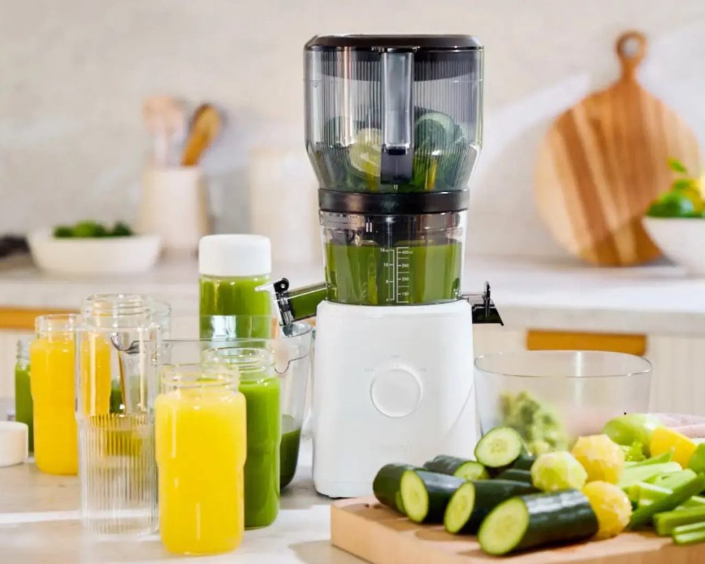 The Nama J2 cold press juicer preparing green juice and citrus juice for a juice fast with fresh ingredients such as cucumbers and leafy vegetables, and citrus