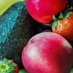 raw food glow — vibrant mix of fresh fruits including strawberries, avocado, grapes, and apple, foods that transform skin from within