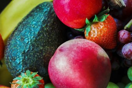 raw food glow — vibrant mix of fresh fruits including strawberries, avocado, grapes, and apple, foods that transform skin from within