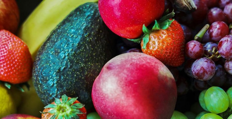 raw food glow — vibrant mix of fresh fruits including strawberries, avocado, grapes, and apple, foods that transform skin from within