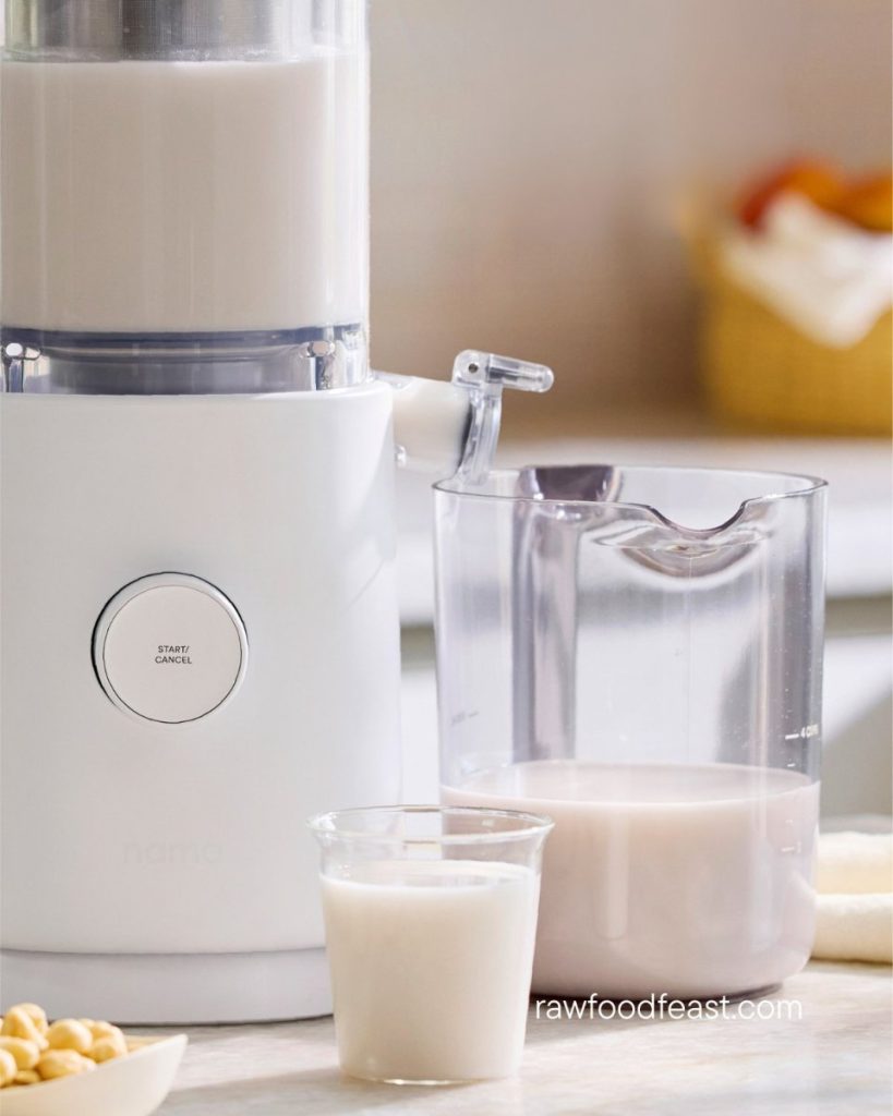 Nama M1 Plant-Based Milk Maker pouring fresh cold-pressed almond milk into glass with smooth creamy texture