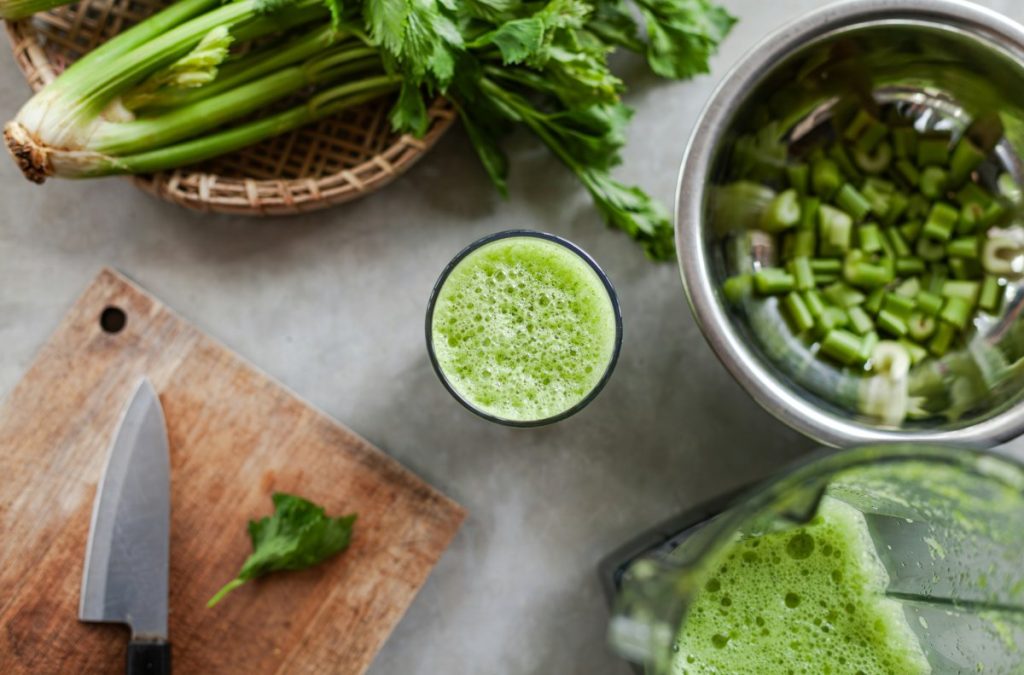 A countertop with a fresh glass of celery juice and celery.