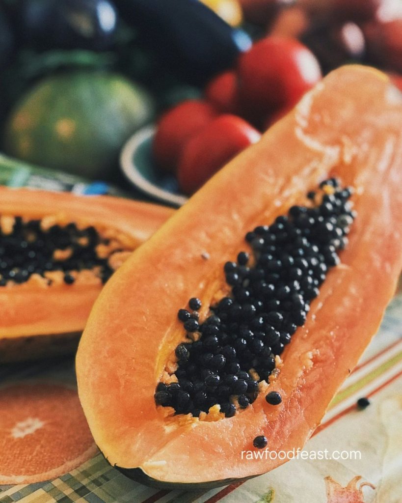 Close-up of a freshly halved ripe papaya with deep orange flesh and glistening black seeds — the papain that gives papaya its benefits for digestion is most concentrated in the raw flesh