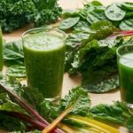 Are oxalates bad for you — glasses and bottles of green juice surrounded by kale, spinach, and rainbow chard