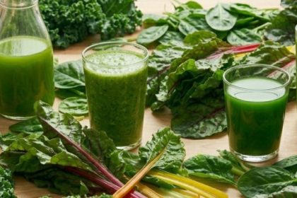 Are oxalates bad for you — glasses and bottles of green juice surrounded by kale, spinach, and rainbow chard