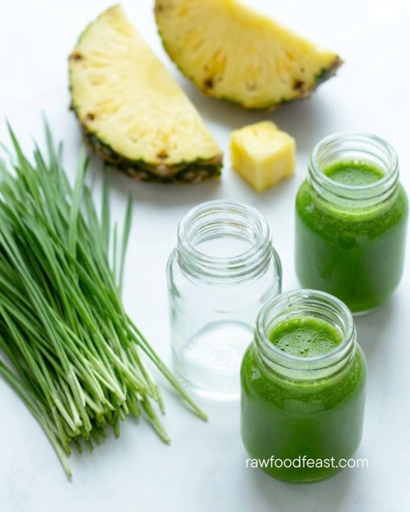 Pineapple juice benefits — wheatgrass and pineapple juice in small glass jars with fresh wheatgrass and pineapple wedge on a white surface