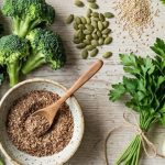 Raw food perimenopause spread — kale, broccoli, celery, seeds, berries, and lemon on a light wood surface