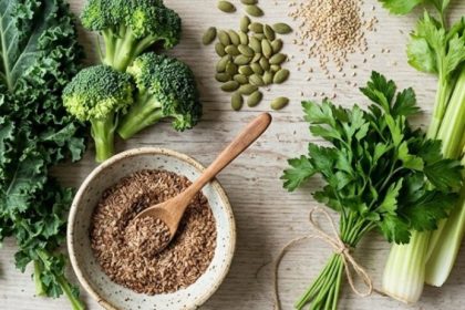 Raw food perimenopause spread — kale, broccoli, celery, seeds, berries, and lemon on a light wood surface