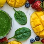 Signs of iron deficiency — green smoothie with fresh mango, kiwi, strawberries, blueberries, and spinach
