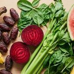 Signs of low potassium — avocado, banana, beet, watermelon, kale, and dates on a light wood surface