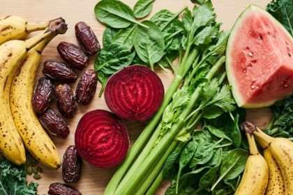 Signs of low potassium — avocado, banana, beet, watermelon, kale, and dates on a light wood surface