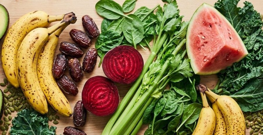 Signs of low potassium — avocado, banana, beet, watermelon, kale, and dates on a light wood surface