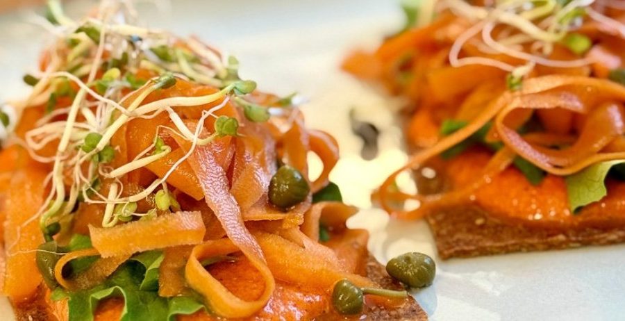 Close-up of raw sundried tomato crackers piled with marinated carrot ribbons, capers, and sprouts — oil-free, gluten-free, made in the dehydrator