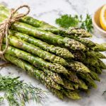 Fresh raw asparagus bunch with lemon and herbs showing the prebiotic asparagus gut health benefit