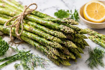 Fresh raw asparagus bunch with lemon and herbs showing the prebiotic asparagus gut health benefit