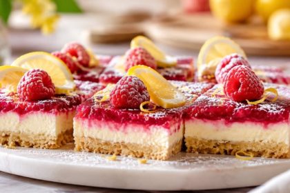 No bake lemon raspberry bars with a coconut date crust, cashew lemon filling, and fresh raspberry layer on a white plate
