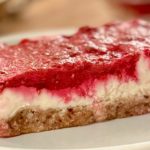 No bake lemon raspberry bars with a coconut date crust, cashew lemon filling, and fresh raspberry layer on a white plate