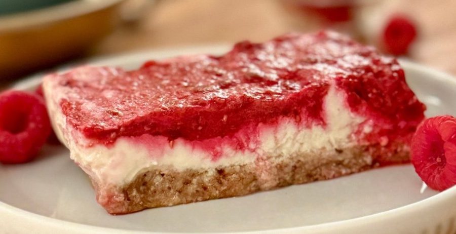 No bake lemon raspberry bars with a coconut date crust, cashew lemon filling, and fresh raspberry layer on a white plate