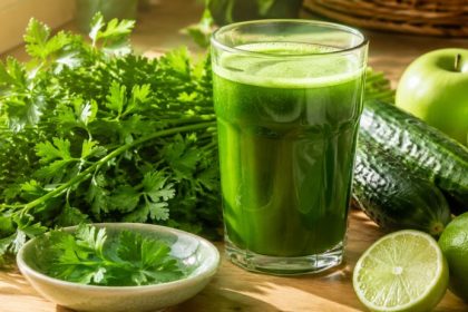 Parsley juice benefits in a glass — fresh parsley, cucumber, green apples, and lime around the daily detox green juice